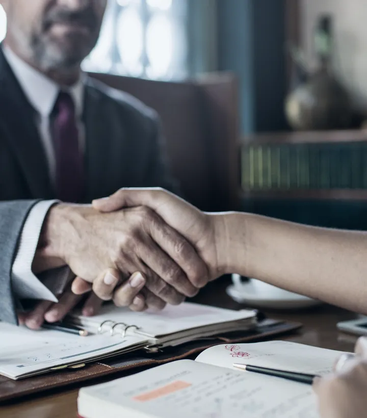 Attorney and client shaking hands across a desk